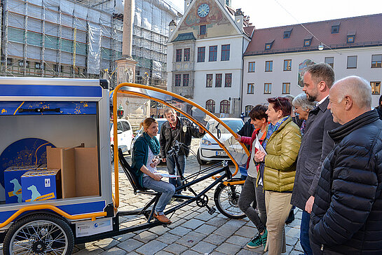 Probesitzen auf dem neuen E-Lastenfahrrad: Klimaschutzmanagerin Marie Hüneke erläutert die Einsatzmöglichkeiten des Info-Mobils. (Foto: Stadt Freising)