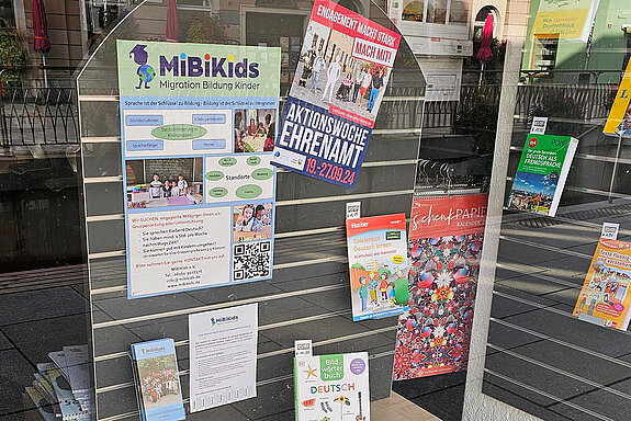 verschiedene Bücher und bunte Plakate in einem Schaufenster