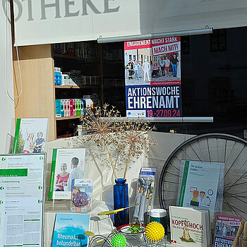 Schaufenster mit Büchern, Igelbällen, einer Holzfigur und einem kleinen Drahtfahrrad