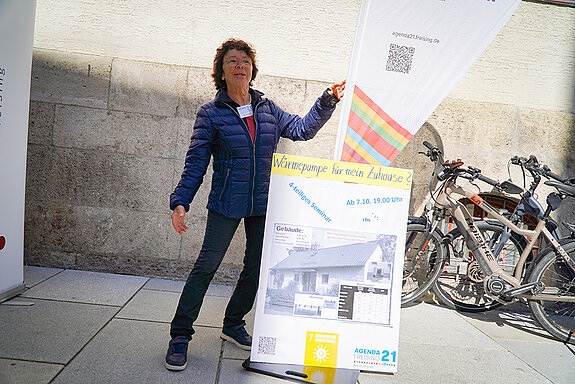 eine Frau präsentiert ein Plakat und eine Beachflag