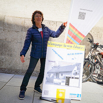 eine Frau präsentiert ein Plakat und eine Beachflag