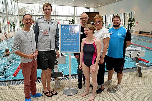 (v. l.) Jürgen Mieskes (Sportreferent), Moritz Zubek (TSV Jahn Freising), Alexander Frederking (Fresch), Stefanie Elsinger, Manuela Wegler (Agenda 21-Gruppe Menschen mit Behinderung), Kevin Blahm (Bademeister). Foto: P. Spanrad sechs Menschen vor einem Schwimmbecken und mit einem blauen Hinweisschild