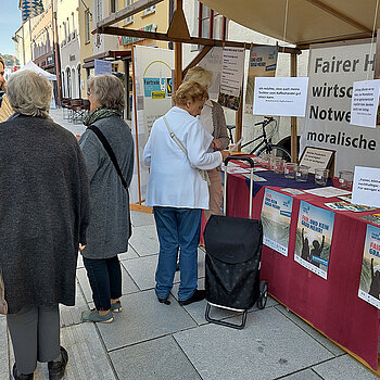 Eine Frau spricht mit zwei älteren Damen während zwei weitere Frauen direkt am Stand stehen und sich unterhalten.