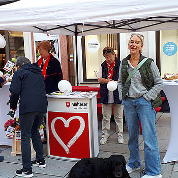 weißer Pavillon mit mehreren Stehtischen, dazwischen mehrere Leute, unter anderm eine Frau mit Hund