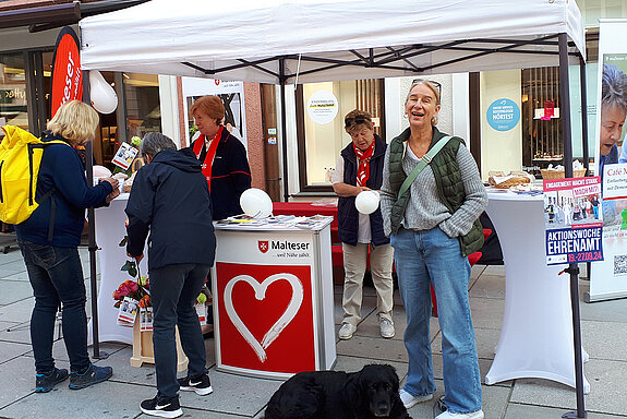 weißer Pavillon mit mehreren Stehtischen, dazwischen mehrere Leute, unter anderm eine Frau mit Hund