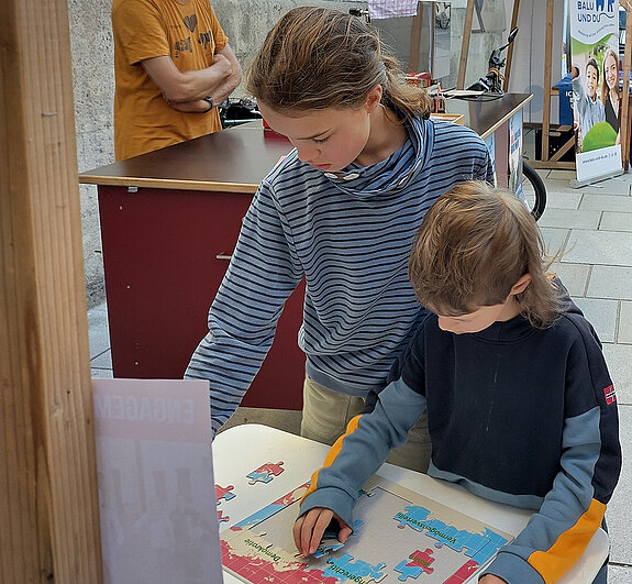 zwei Kinder setzen das „Eine-faire-Welt-Puzzle“ zusammen