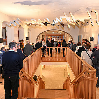 Aufmerksam verfolgten im Treppenhaus des Asamgebäudes die Besucherinnen und Besucher die einführenden Worte zur Studioausstellung. (Foto. Stadt Freising)